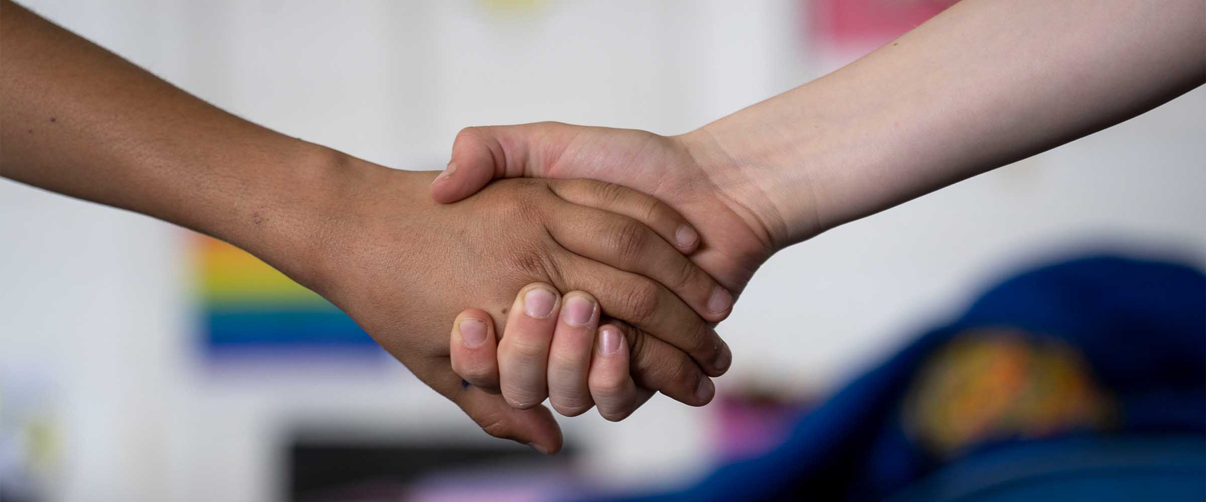 A close up of two young people holding hands supportively.