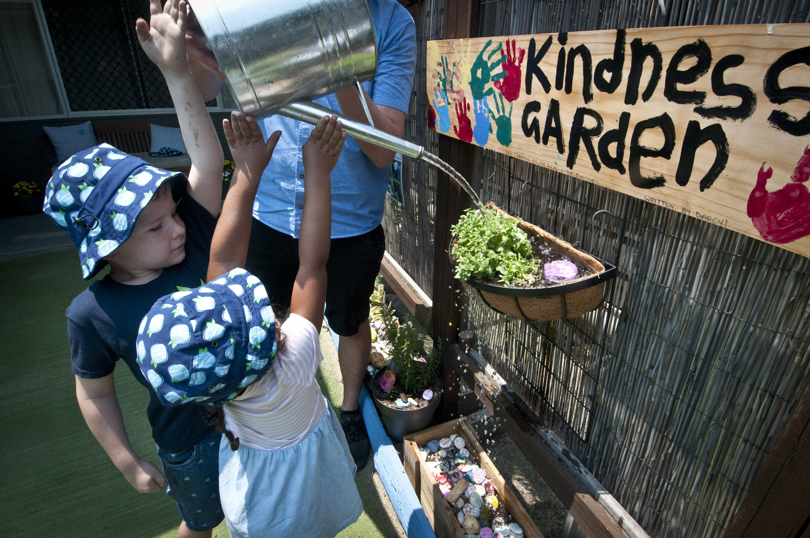 Two children and an adult, watering plants