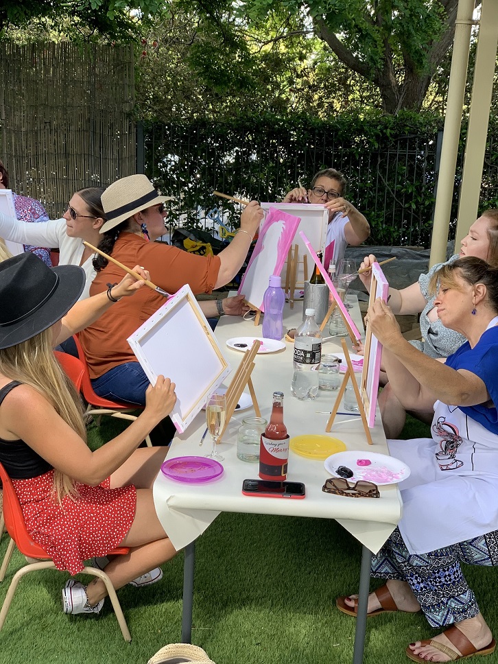 A group of adults sitting outside doing artwork