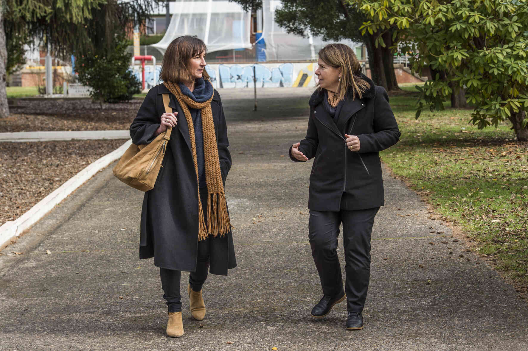 Two adults walking through a park