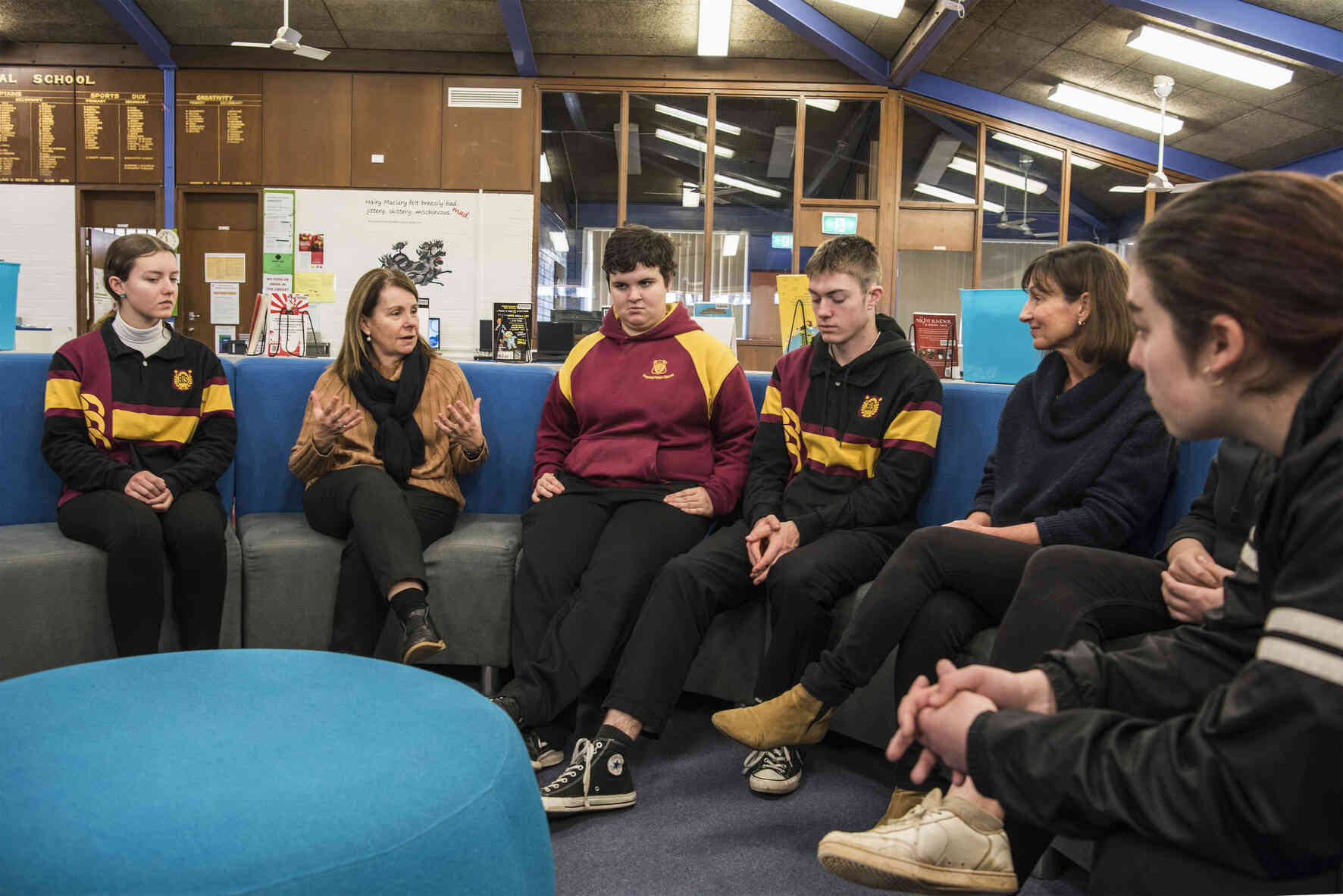 An adult sitting with a group of adolescents 