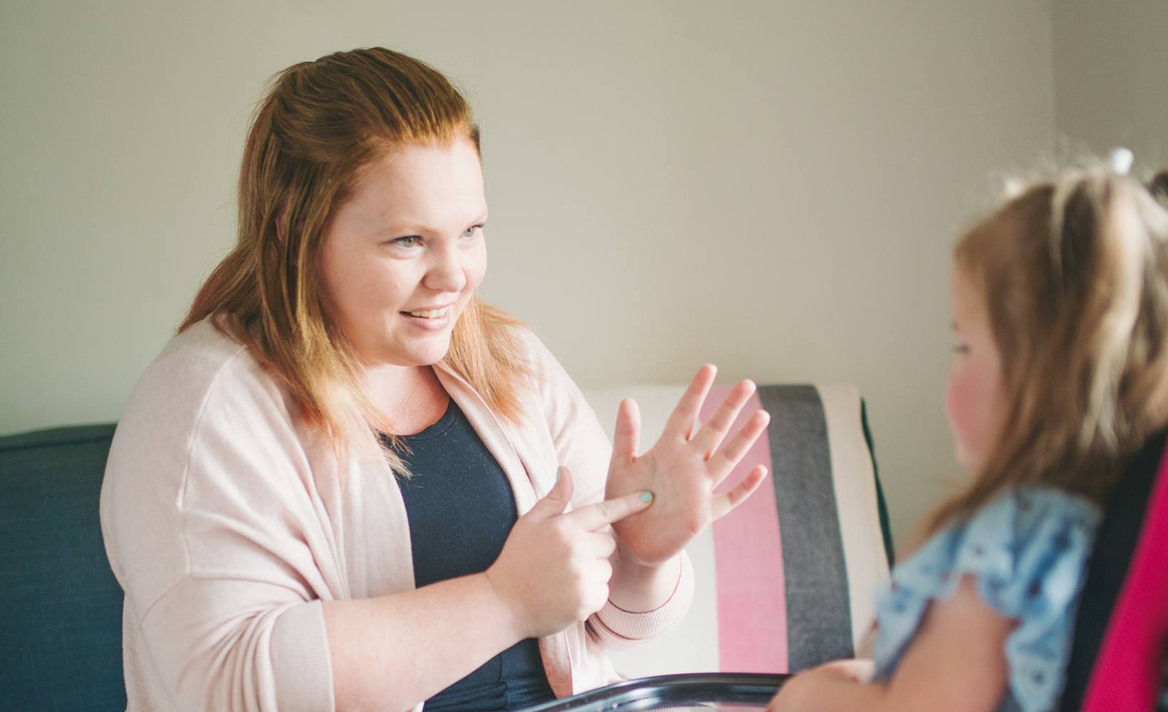 An educator teaching sign-language to a young child
