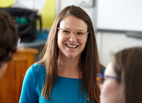 Photo of educator wearing glasses smiling at colleagues.
