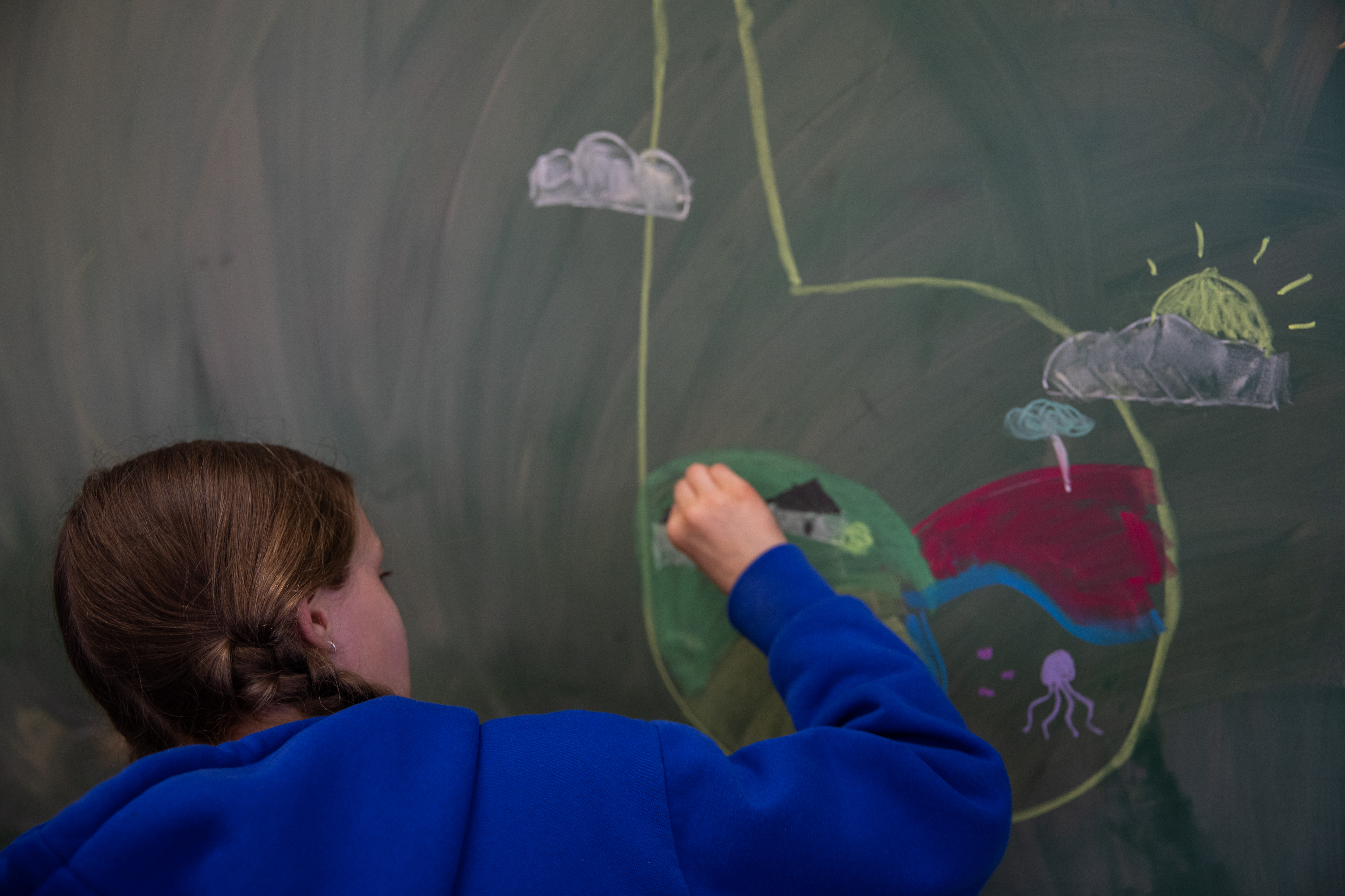 A child drawing on a blackboard with chalk