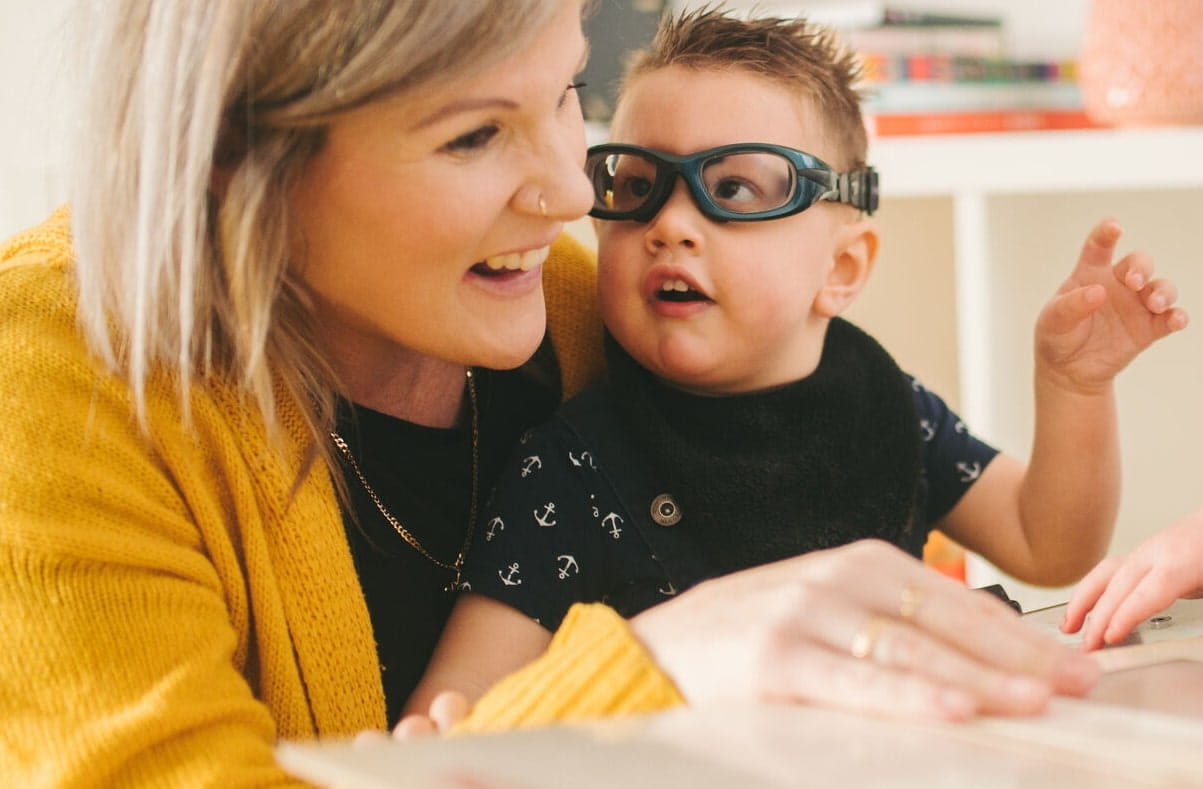 Educator with disabled toddler sitting on her lap